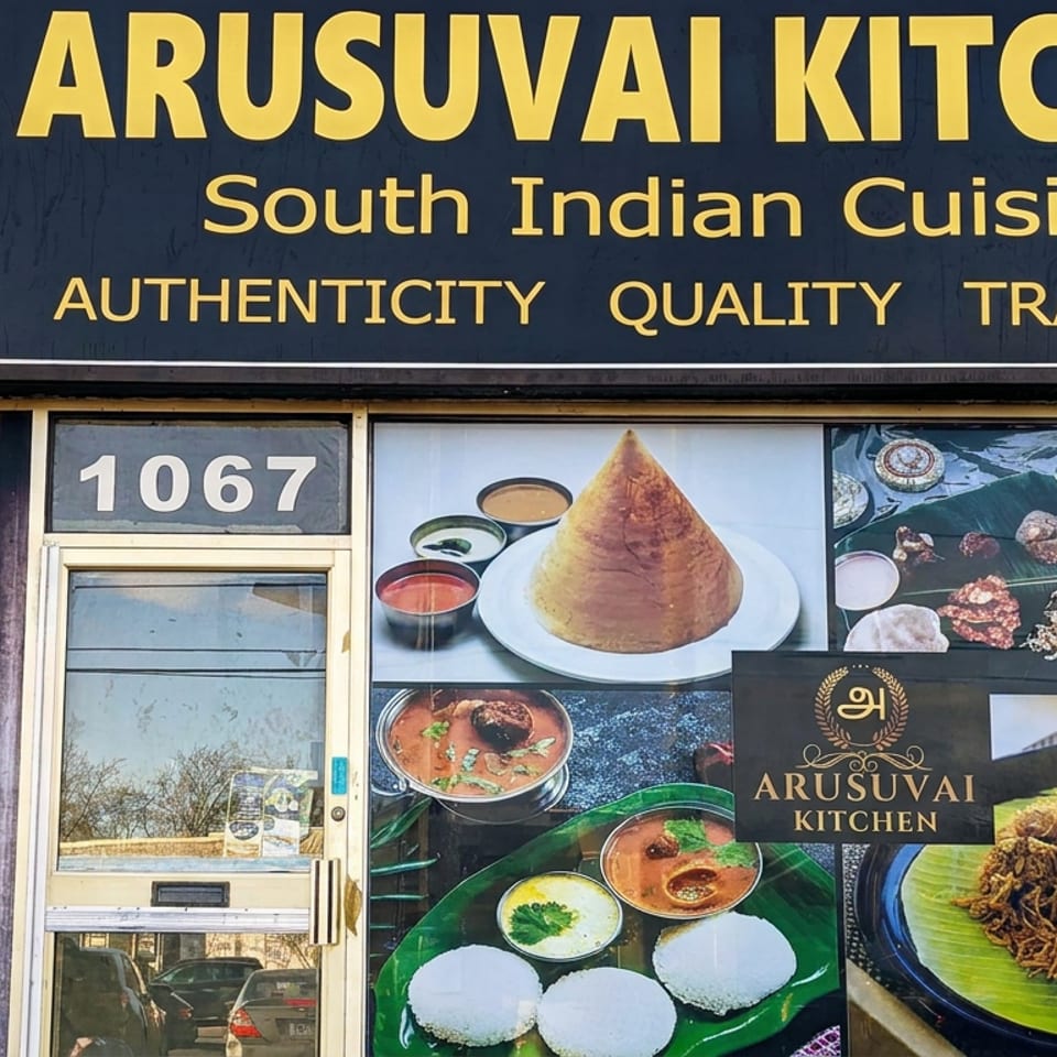 Arusuvai Kitchen storefront at 1067, featuring South Indian cuisine signage and window displays of dosa, rice cakes, and savory dishes.